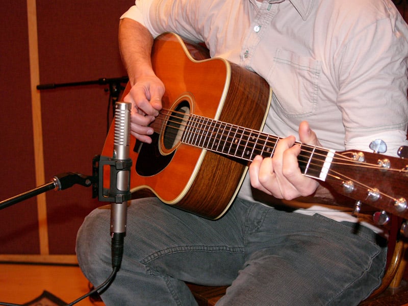 A mono R-122 positioned at about the 12th fret of an acoustic guitar, a few inches off the neck