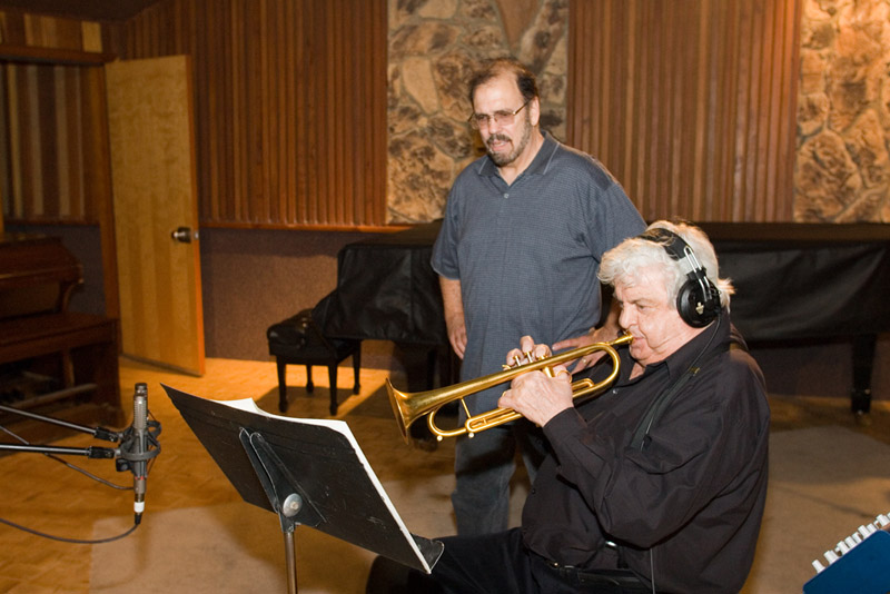 Maynard Ferguson playing trumpet into two R-122 ribbon mics while producer Gary Grant looks on